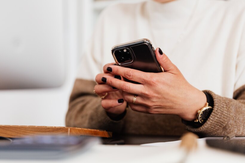 Hands holding a phone at a desk