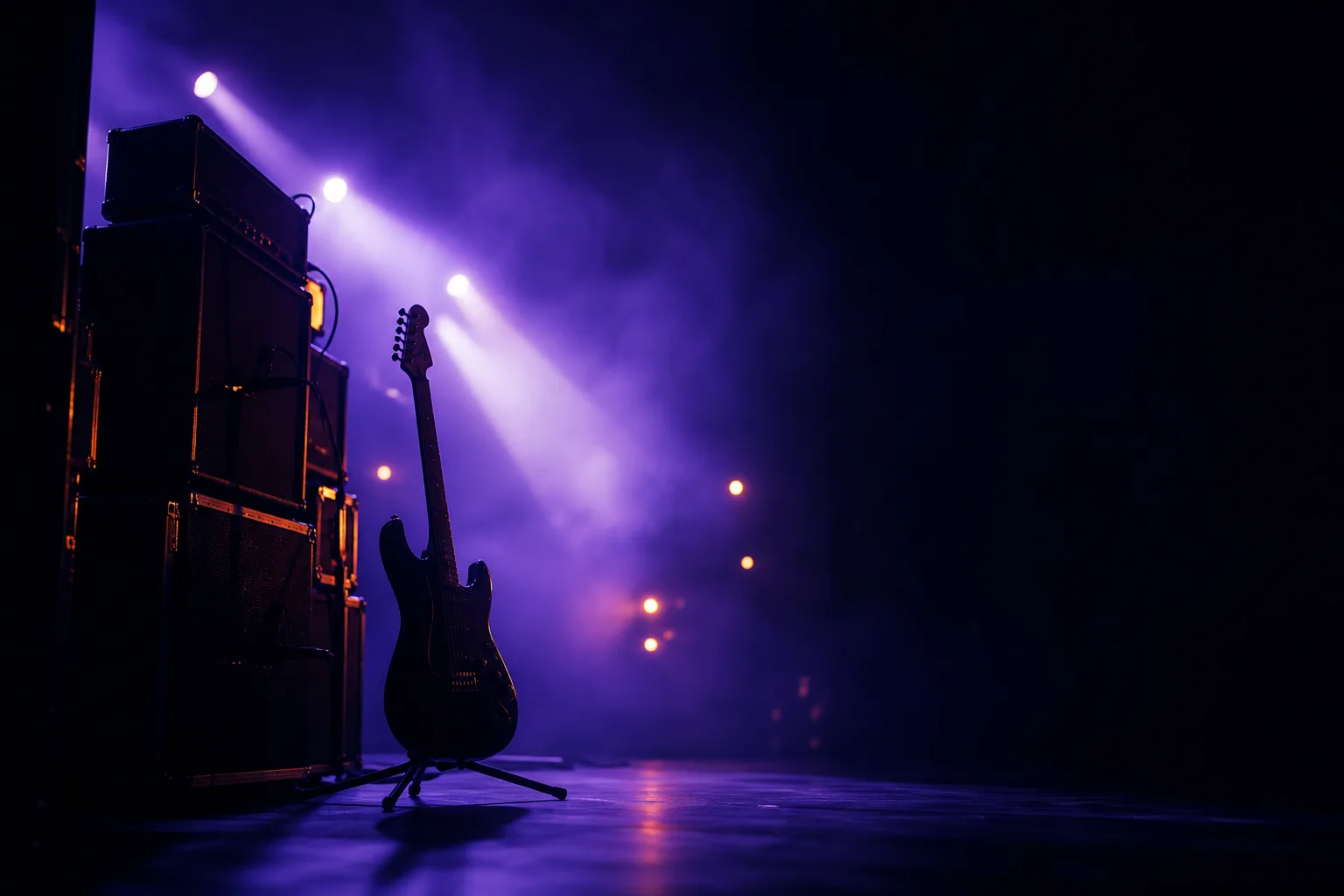 An electric guitar on a stand beside a stack of amplifiers on a hazy stage lit in violet